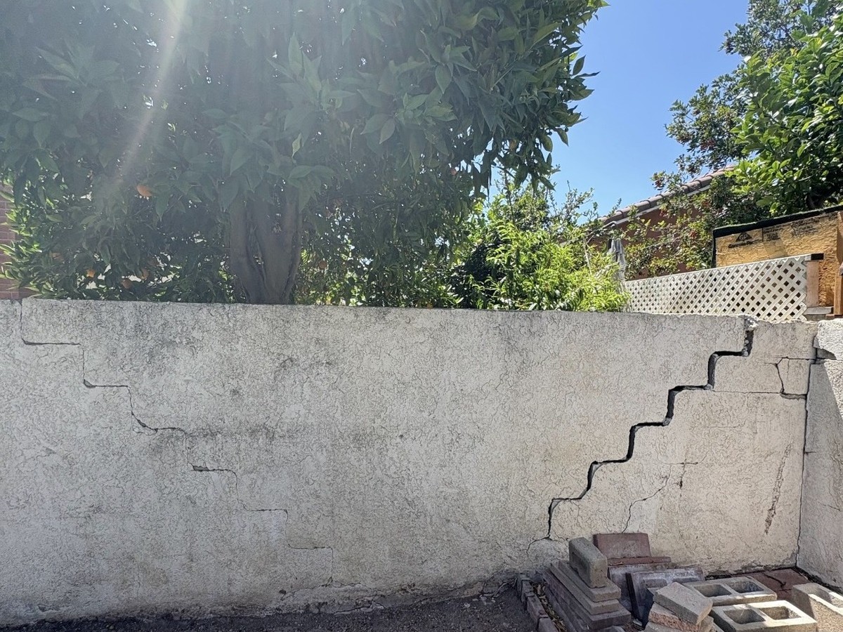 Before: wall with a large stair-step crack and stacked masonry debris