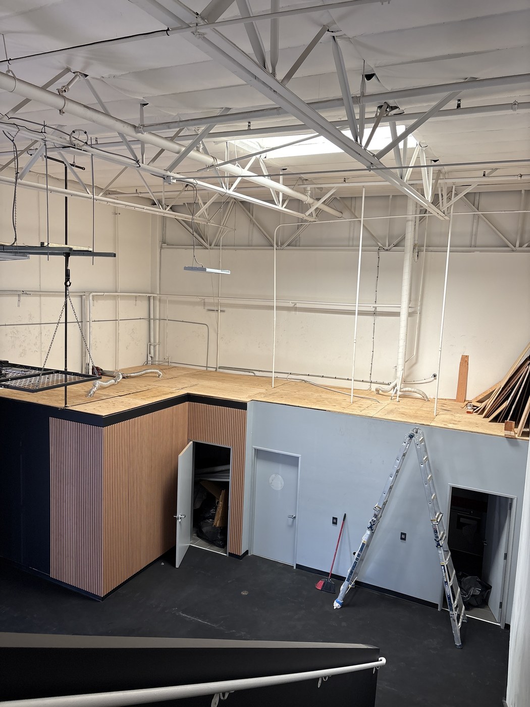 Wide view of mezzanine framing above a finished wood-slat accent wall