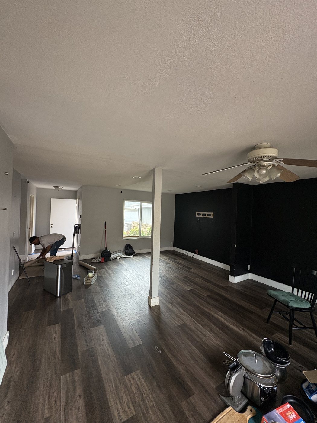Living room mid-renovation with new wall framing, fresh drywall texture and flooring install