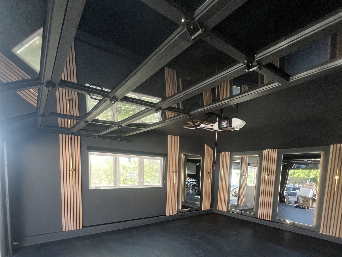 After: garage converted into a home gym with black walls, wood slat accents and mirrors